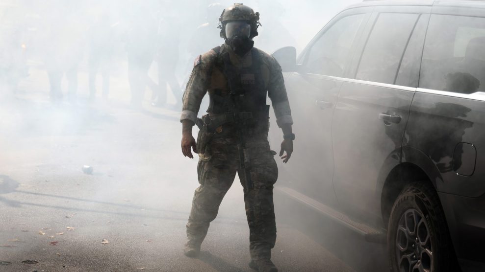 A Border Patrol agent walking through a cloud of tear gas next to a car.