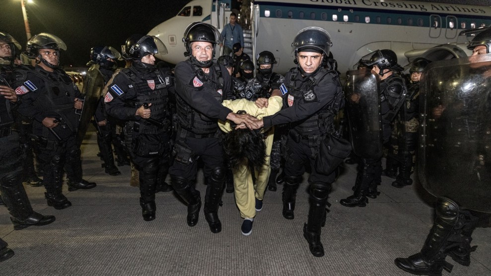 Two prison guards hold a man's held toward the ground as they walk him toward the camera