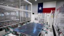 A solar panel in a factory in front of a Texas flag.