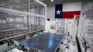 A solar panel in a factory in front of a Texas flag.